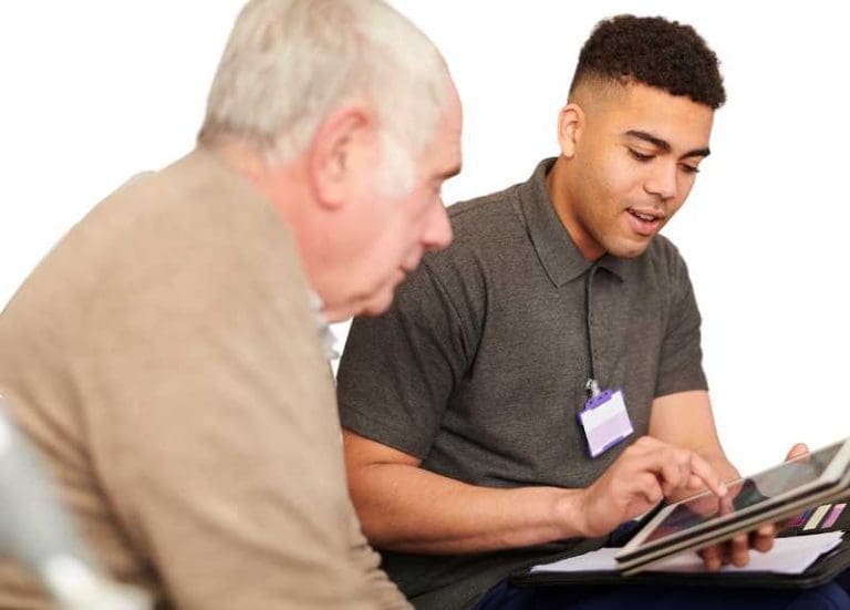 Young Adult Working With Senior Man On Tablet