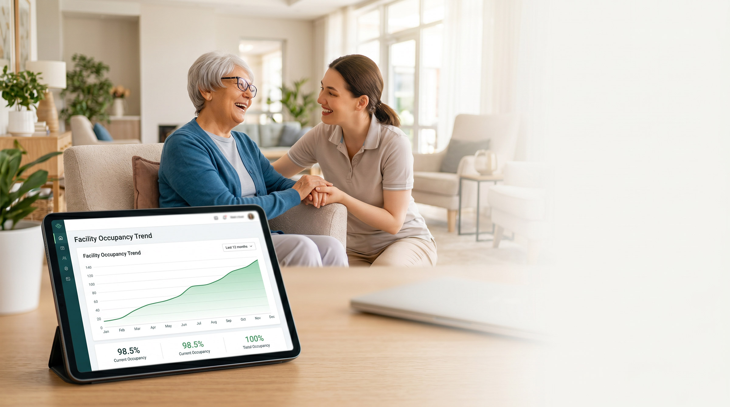 Older adult resident and caregiver smiling and holding hands in a bright living space with a tablet showing a facility occupancy trend graph in the foreground.