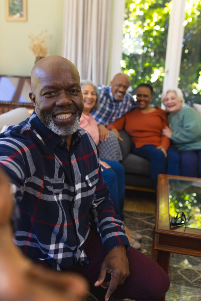 Group of seniors smiling and sitting together in a living room during a social activity in the senior living community.