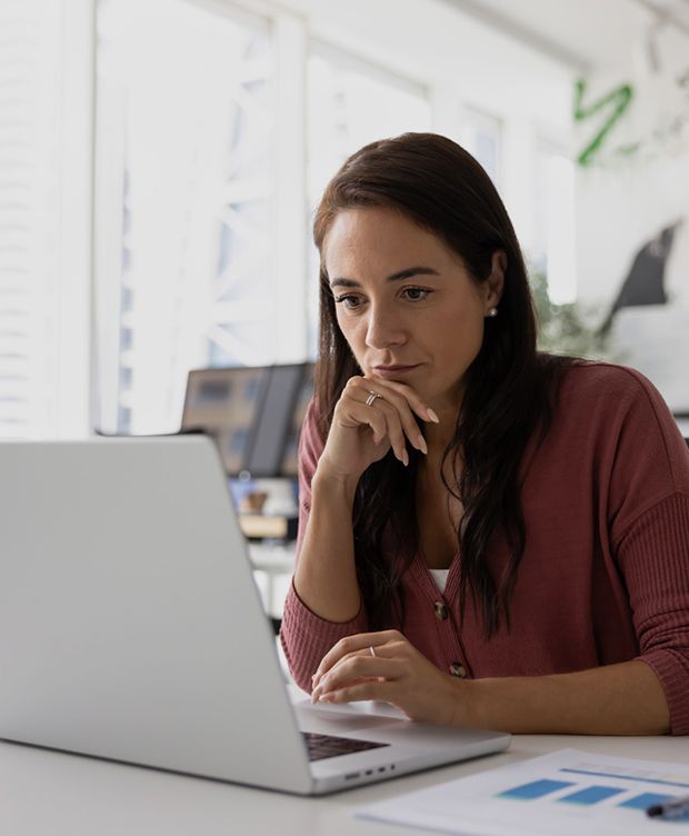 Woman focused on working at a laptop in a bright office setting.