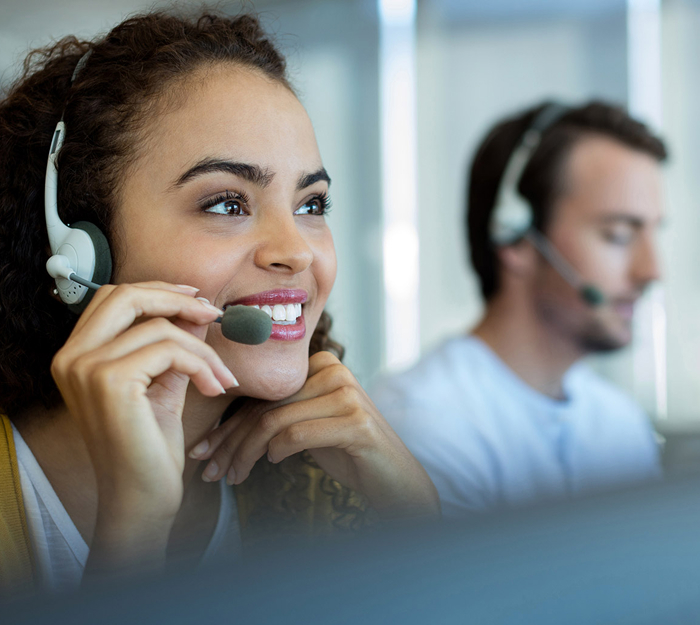 Customer service representatives wearing headsets engaged in communication at an office.