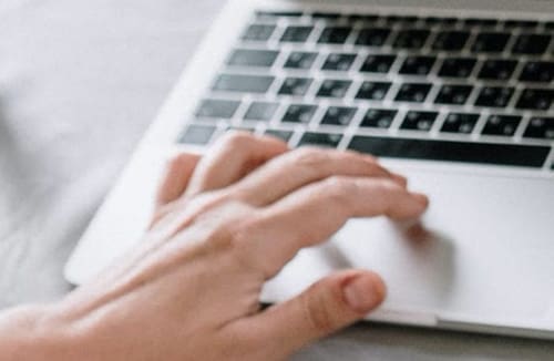 A person typing on a laptop keyboard, focusing on the hand and keyboard.
