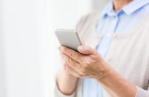 Person holding and using a smartphone indoors in a relaxed setting.