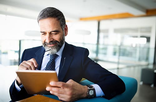 Man in business attire using a tablet in a modern office setting.