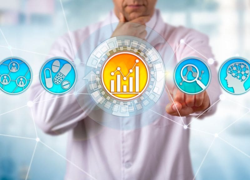 Person interacting with digital icons displaying data charts and healthcare symbols on a transparent screen.