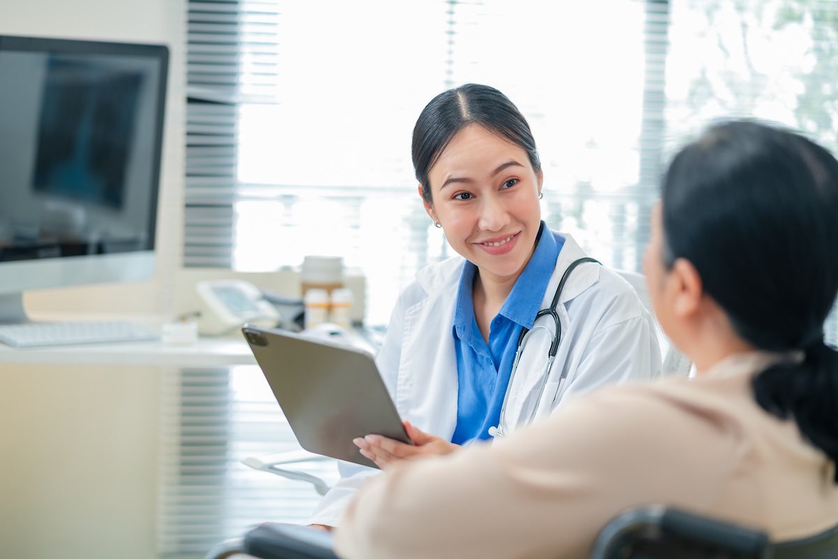 Healthcare professional consulting with a patient using a digital tablet in a medical office setting